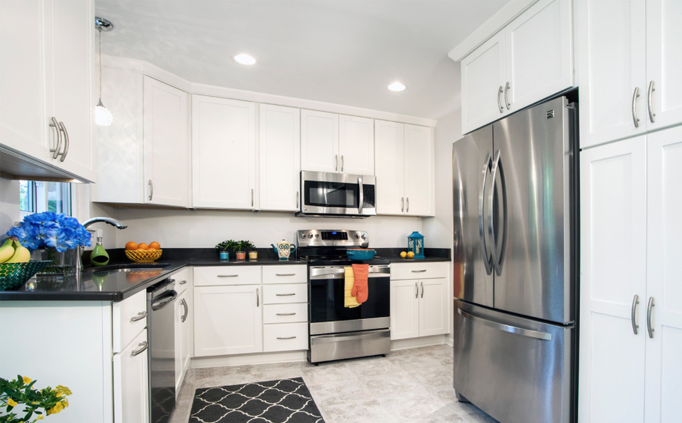Example of a transitional l-shaped medium tone wood floor kitchen design with an undermount sink, shaker cabinets, white cabinets, white backsplash, stainless steel appliances and an island