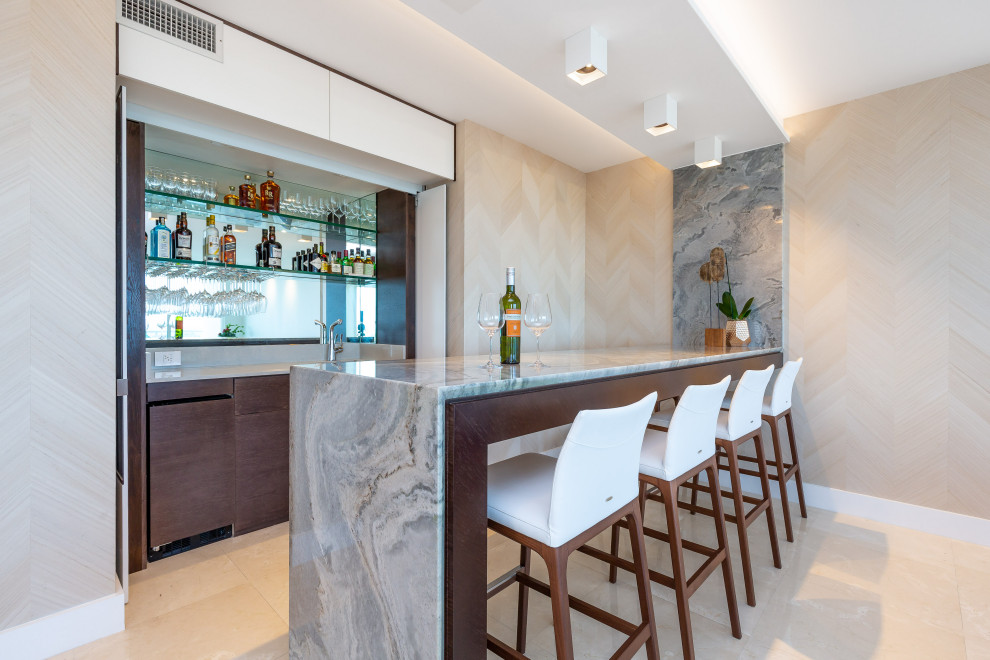 This is an example of a contemporary seated home bar in Miami with an undermount sink, flat-panel cabinets, medium wood cabinets, marble benchtops, mirror splashback, beige floor and multi-coloured benchtop.