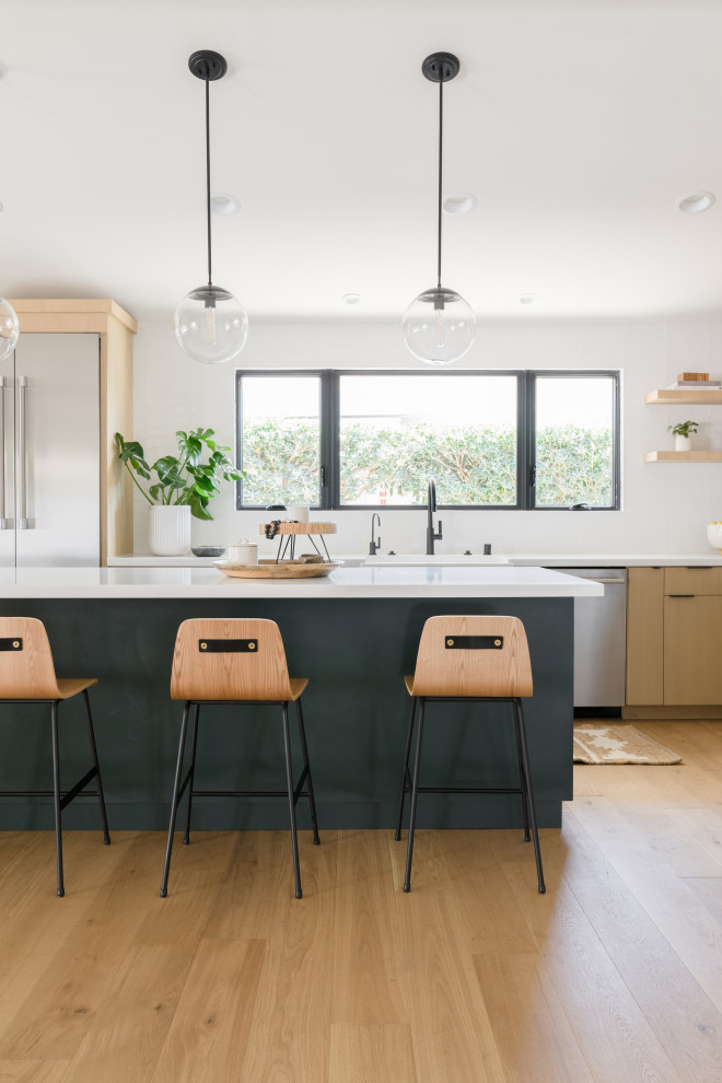 Mid-sized scandinavian l-shaped eat-in kitchen in Orange County with a farmhouse sink, flat-panel cabinets, brown cabinets, quartz benchtops, white splashback, ceramic splashback, stainless steel appliances, light hardwood floors, with island, brown floor, white benchtop and vaulted.