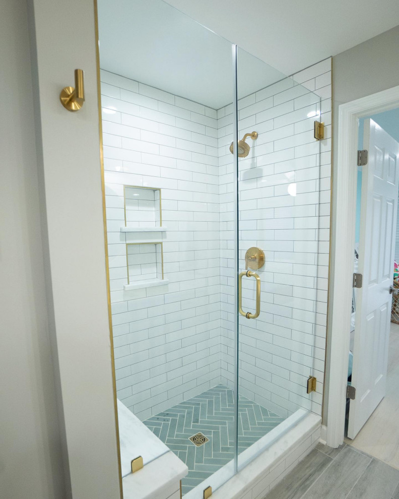 This is an example of a large nautical ensuite bathroom in Charleston with shaker cabinets, white cabinets, an alcove shower, white tiles, ceramic tiles, white walls, wood-effect flooring, engineered stone worktops, grey floors, a hinged door, white worktops, a wall niche, double sinks, a built in vanity unit and tongue and groove walls.