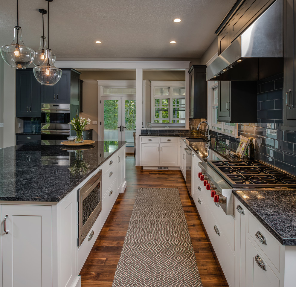 Open concept kitchen - large transitional single-wall medium tone wood floor open concept kitchen idea with an undermount sink, shaker cabinets, gray cabinets, granite countertops, gray backsplash, ceramic backsplash, stainless steel appliances and an island