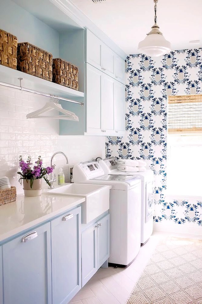 Country laundry room in Dallas with a farmhouse sink, shaker cabinets, blue cabinets, light hardwood floors, a side-by-side washer and dryer, beige floor, white benchtop and multi-coloured walls.