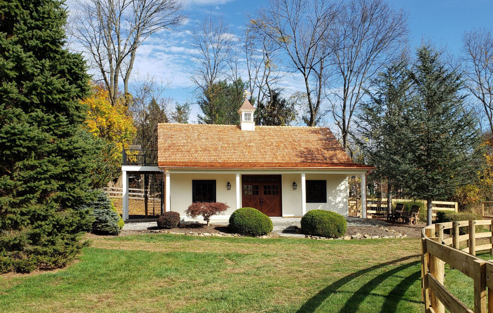 Cette image montre une petite façade de maison blanche rustique en bois et planches et couvre-joints à un étage avec un toit à deux pans, un toit mixte et un toit marron.