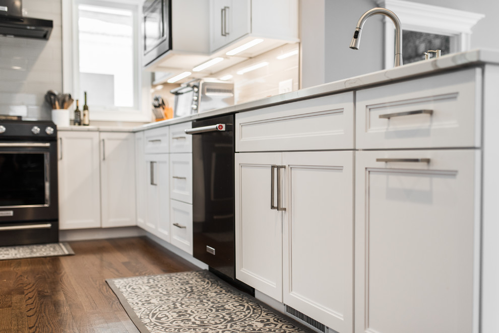 Example of a mid-sized transitional l-shaped medium tone wood floor and brown floor eat-in kitchen design in Chicago with an undermount sink, recessed-panel cabinets, white cabinets, quartzite countertops, gray backsplash, subway tile backsplash, black appliances, no island and multicolored countertops