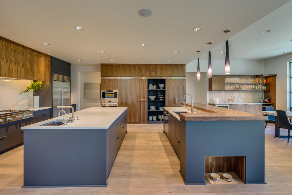 Photo of an expansive contemporary eat-in kitchen in Portland with an undermount sink, flat-panel cabinets, medium wood cabinets, quartzite benchtops, beige splashback, stone slab splashback, stainless steel appliances, medium hardwood floors and multiple islands.