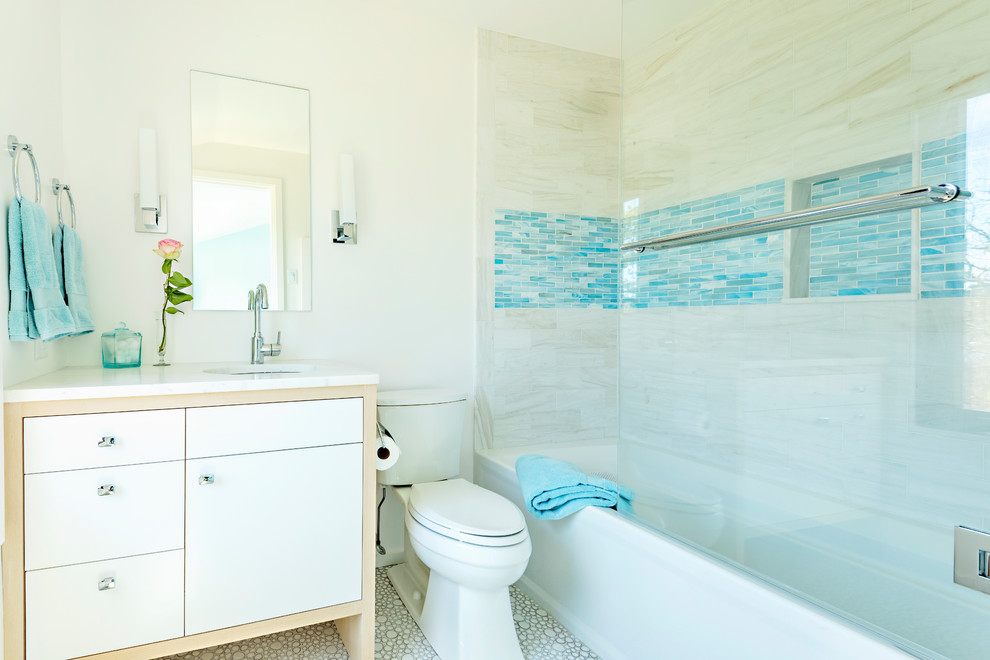 Mid-sized beach style kids bathroom in Boston with flat-panel cabinets, beige cabinets, a shower/bathtub combo, a two-piece toilet, beige tile, white walls, an undermount sink, grey floor, a sliding shower screen and white benchtops.