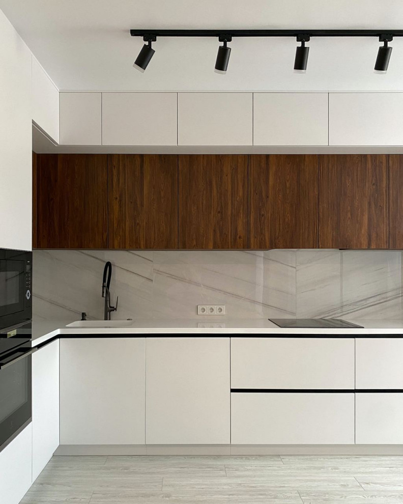 This is an example of a large contemporary l-shaped eat-in kitchen in Moscow with an integrated sink, flat-panel cabinets, white cabinets, solid surface benchtops, grey splashback, porcelain splashback, black appliances, laminate floors, no island, turquoise floor and white benchtop.