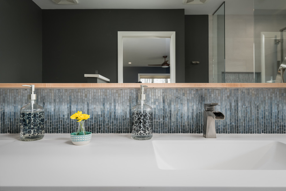 Idee per una stanza da bagno padronale minimalista di medie dimensioni con ante lisce, ante in legno chiaro, piastrelle blu, piastrelle a mosaico, pareti grigie, pavimento con piastrelle in ceramica, top in superficie solida, pavimento marrone, top bianco, due lavabi e mobile bagno sospeso