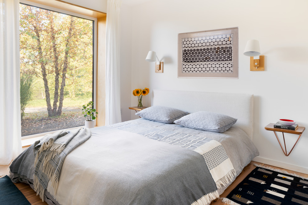 Modernes Schlafzimmer mit weißer Wandfarbe, braunem Holzboden und braunem Boden in New York