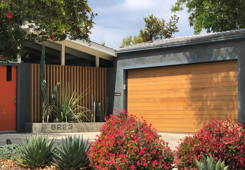Photo of a medium sized midcentury front driveway partial sun garden for winter in Los Angeles with a garden path, concrete paving and a metal fence.