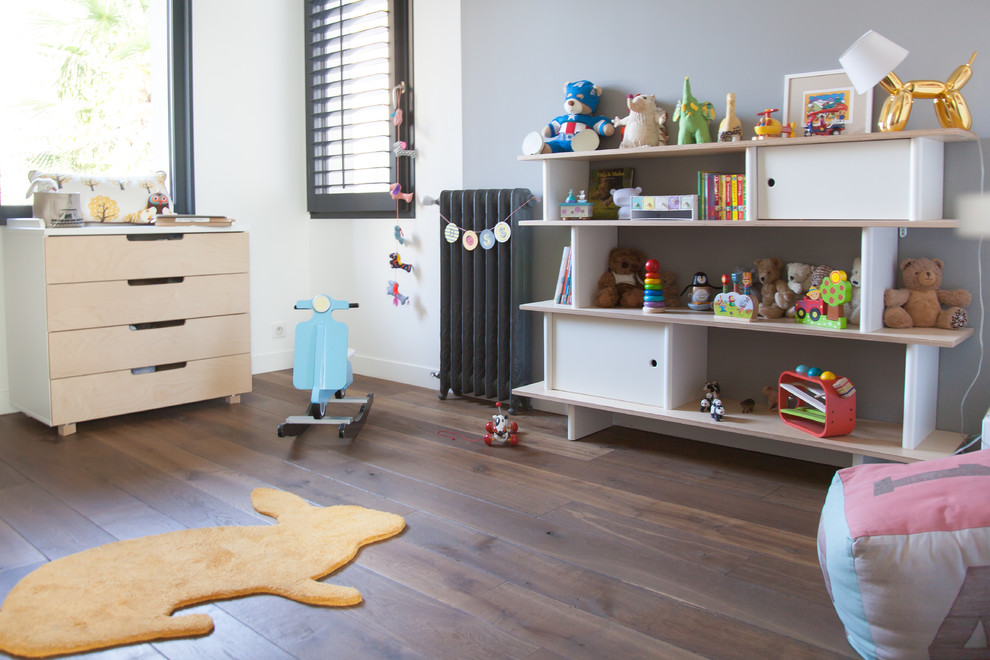 Idée de décoration pour une chambre d'enfant de 1 à 3 ans bohème de taille moyenne avec un mur gris et un sol en bois brun.