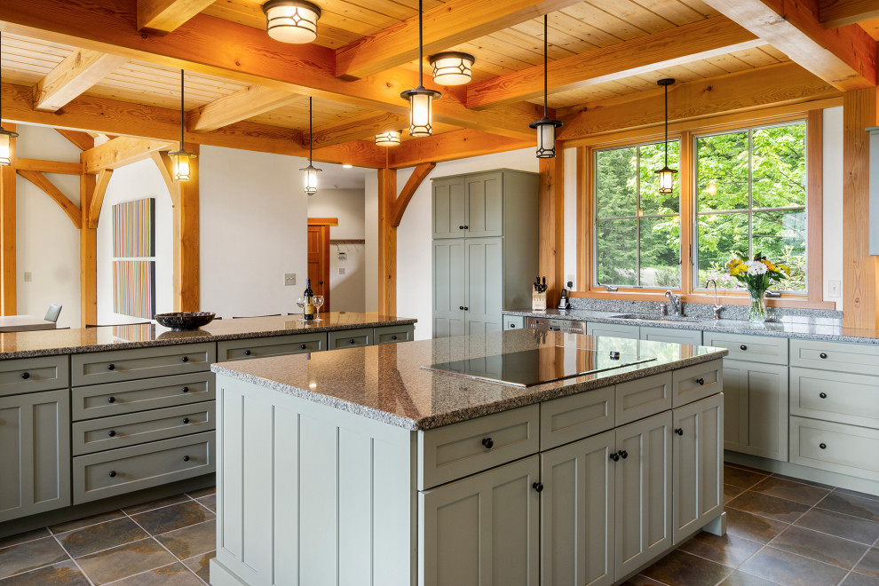 Photo of a large arts and crafts l-shaped open plan kitchen in Other with an undermount sink, shaker cabinets, green cabinets, granite benchtops, stainless steel appliances, slate floors, multiple islands, grey floor and exposed beam.