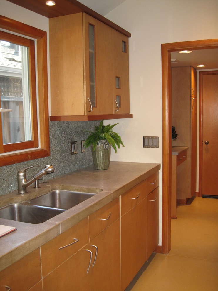 Mid-sized asian galley separate kitchen in San Francisco with concrete floors, an undermount sink, flat-panel cabinets, light wood cabinets, concrete benchtops, green splashback, cement tile splashback and stainless steel appliances.