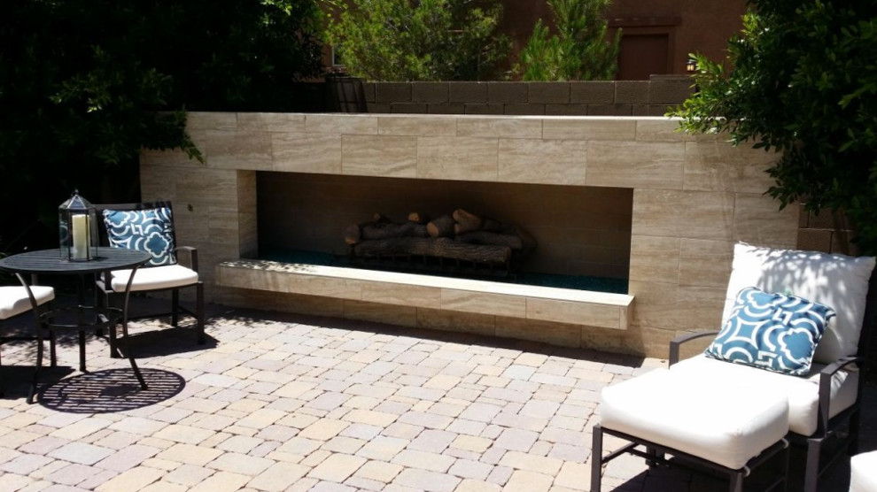 Photo of a large contemporary backyard patio in Phoenix with a fire feature, natural stone pavers and no cover.