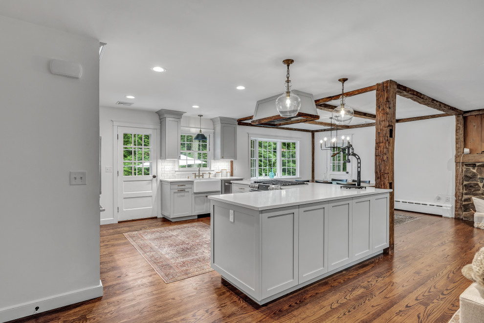 Inspiration for a large country u-shaped medium tone wood floor, brown floor and exposed beam eat-in kitchen remodel in New York with a farmhouse sink, shaker cabinets, gray cabinets, quartz countertops, white backsplash, subway tile backsplash, stainless steel appliances, an island and white countertops