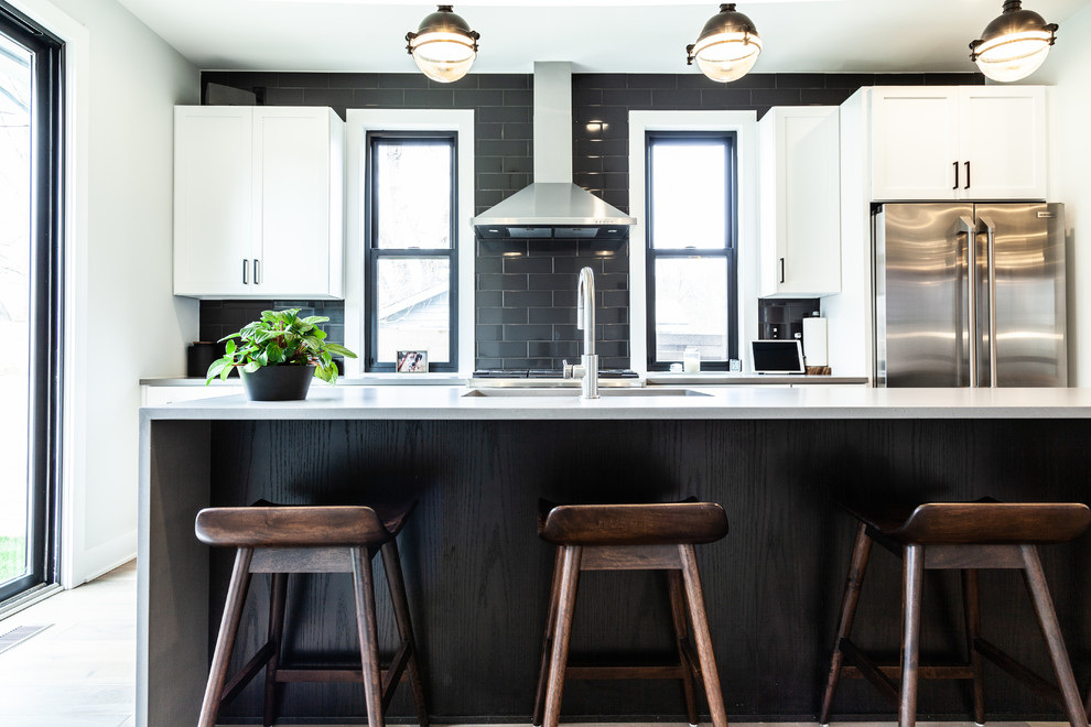 Inspiration for a contemporary galley kitchen in Indianapolis with an undermount sink, shaker cabinets, white cabinets, black splashback, subway tile splashback, stainless steel appliances, with island and white benchtop.