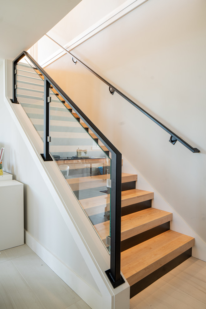 Imagen de escalera contemporánea de tamaño medio con escalones de madera, contrahuellas de madera pintada y barandilla de vidrio