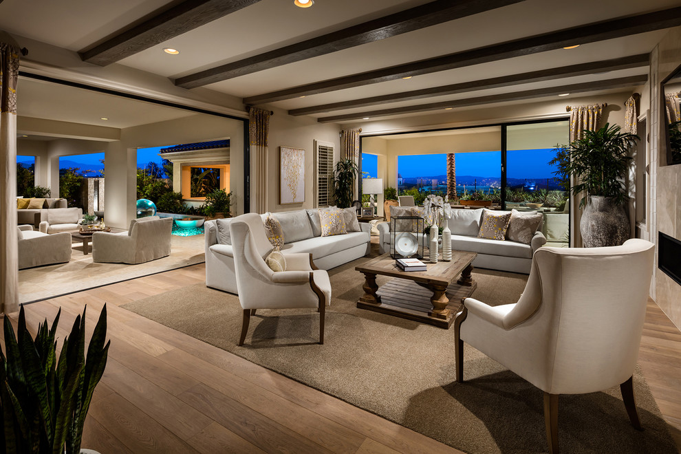 Photo of a large mediterranean open concept family room in San Diego with beige walls, light hardwood floors, a ribbon fireplace, a stone fireplace surround and a wall-mounted tv.