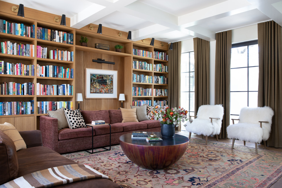 Aménagement d'une salle de séjour classique avec une bibliothèque ou un coin lecture, un mur blanc, un sol en bois brun, un sol marron et poutres apparentes.