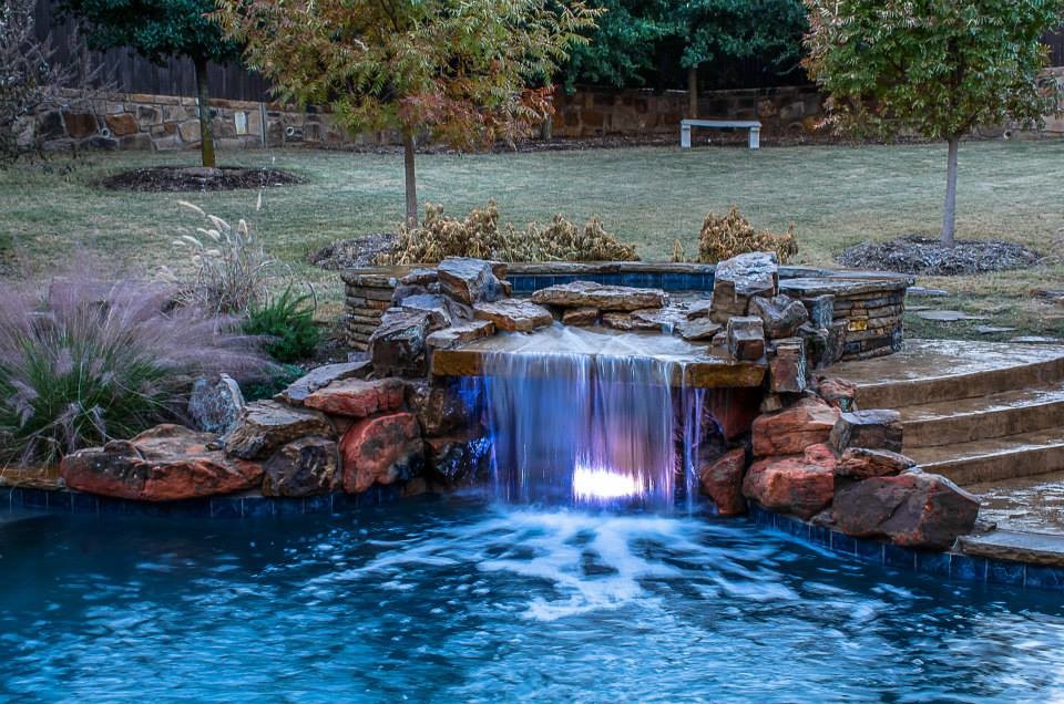 Inspiration for a large mediterranean backyard custom-shaped pool in Dallas with a water feature and concrete pavers.