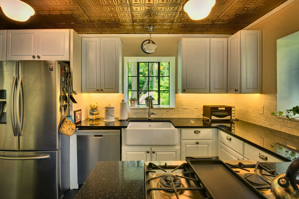 Small mountain style u-shaped slate floor eat-in kitchen photo in New York with a farmhouse sink, raised-panel cabinets, white cabinets, soapstone countertops, white backsplash, subway tile backsplash and stainless steel appliances