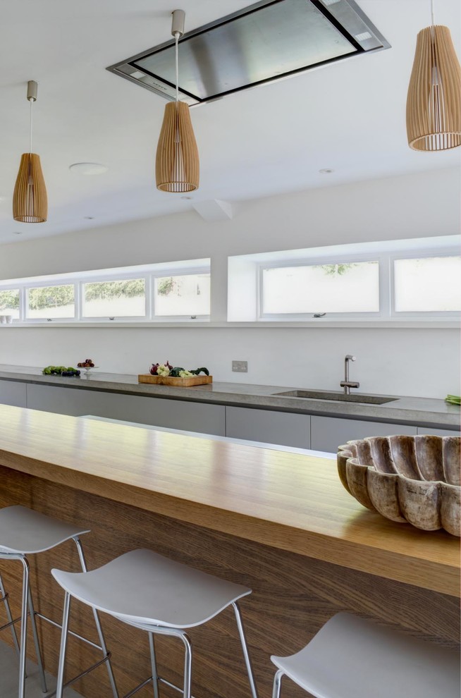 Inspiration for an expansive contemporary single-wall open plan kitchen in London with an integrated sink, flat-panel cabinets, white cabinets, concrete benchtops, cement tiles, a peninsula, grey floor and grey benchtop.
