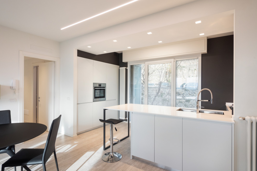 Design ideas for a mid-sized contemporary u-shaped open plan kitchen in Other with an undermount sink, flat-panel cabinets, white cabinets, quartzite benchtops, grey splashback, stainless steel appliances, porcelain floors, with island, beige floor and white benchtop.