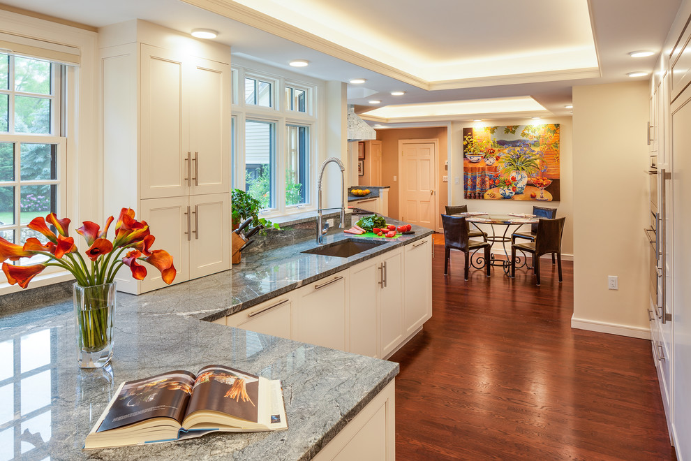 Open concept kitchen - large transitional galley medium tone wood floor open concept kitchen idea in Boston with an undermount sink, shaker cabinets, white cabinets, granite countertops, multicolored backsplash, stone slab backsplash, stainless steel appliances and a peninsula