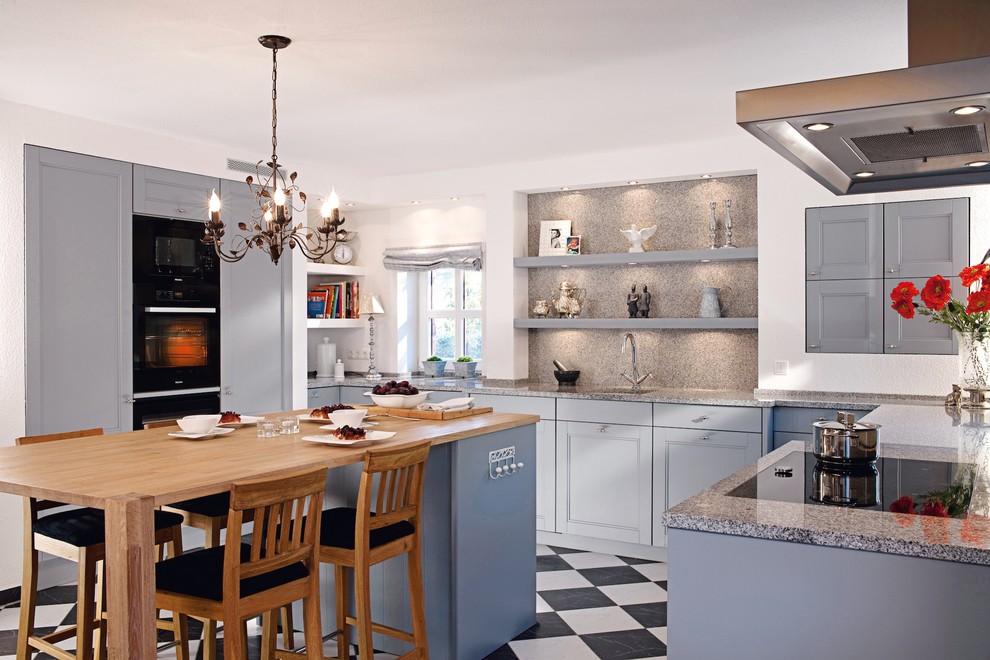 This is an example of a mid-sized traditional u-shaped separate kitchen in Berlin with an undermount sink, beaded inset cabinets, blue cabinets, granite benchtops, grey splashback, stone slab splashback, panelled appliances, ceramic floors and with island.