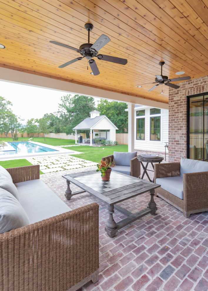 Inspiration for a large country brick back porch remodel in Austin with a roof extension