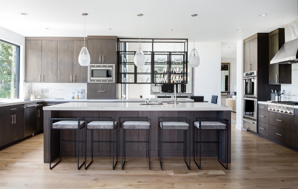 Photo of a contemporary kitchen in Salt Lake City with an undermount sink, flat-panel cabinets, dark wood cabinets, white splashback, stainless steel appliances, light hardwood floors, with island and beige floor.