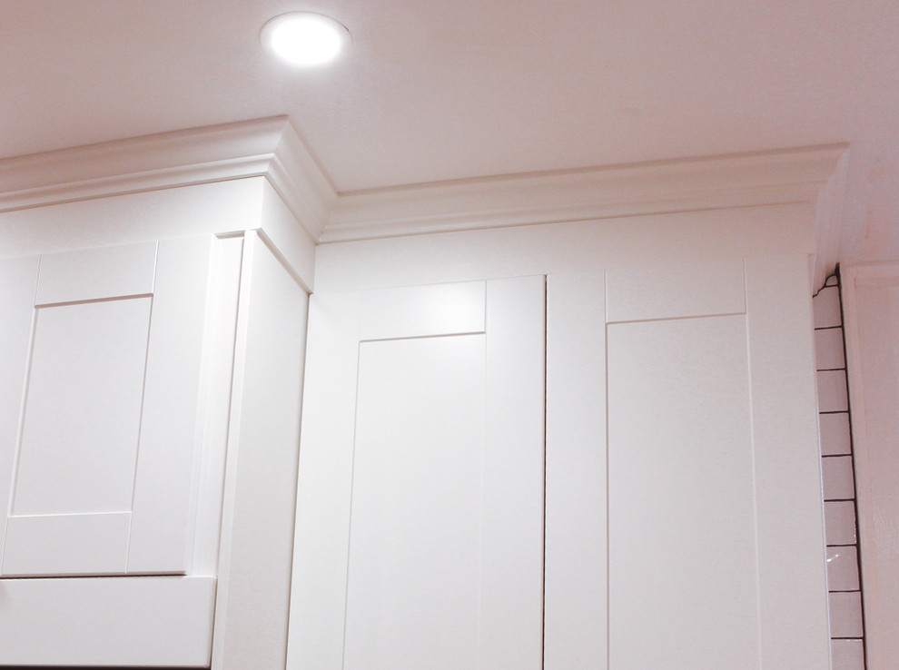 Small transitional l-shaped light wood floor and brown floor eat-in kitchen photo in Toronto with an undermount sink, shaker cabinets, white cabinets, quartz countertops, white backsplash, ceramic backsplash, stainless steel appliances and a peninsula