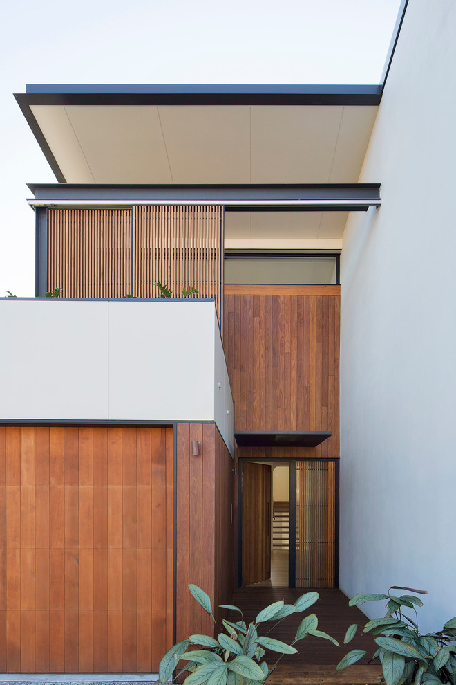 This is an example of a mid-sized contemporary two-storey townhouse exterior in Sydney with wood siding and a flat roof.