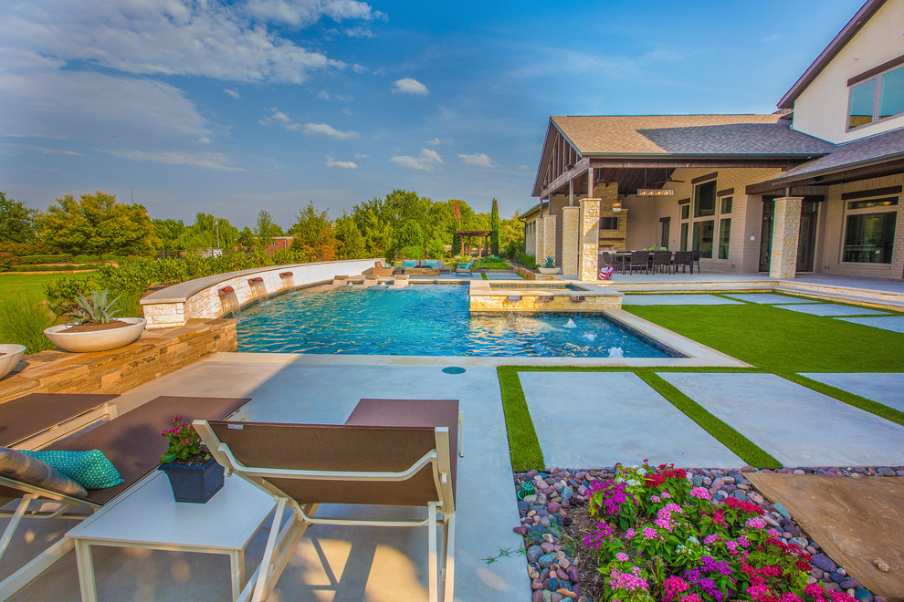 This is an example of a large transitional backyard l-shaped pool in Dallas with a water feature and concrete slab.