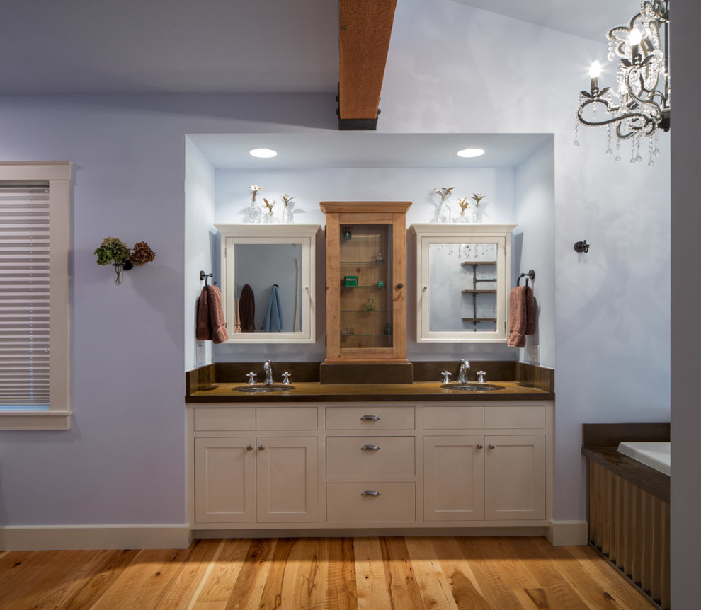 Design ideas for a large country master bathroom in Other with recessed-panel cabinets, white cabinets, a corner tub, blue walls and medium hardwood floors.