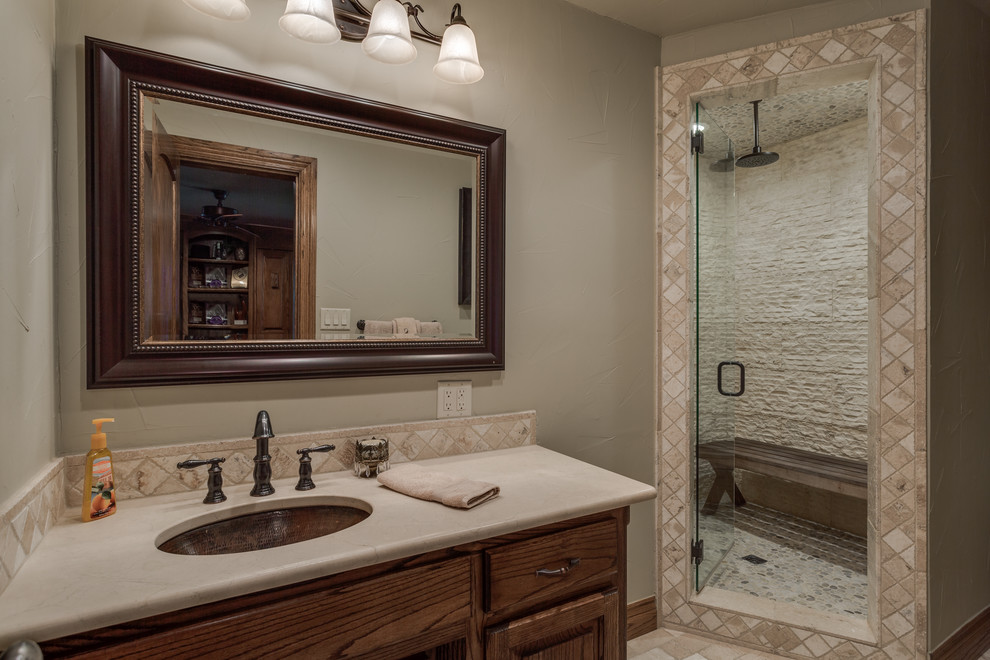 Large traditional 3/4 bathroom in Dallas with raised-panel cabinets, dark wood cabinets, an alcove shower, a two-piece toilet, beige tile, travertine, beige walls, travertine floors, an undermount sink, marble benchtops, beige floor, a hinged shower door and beige benchtops.