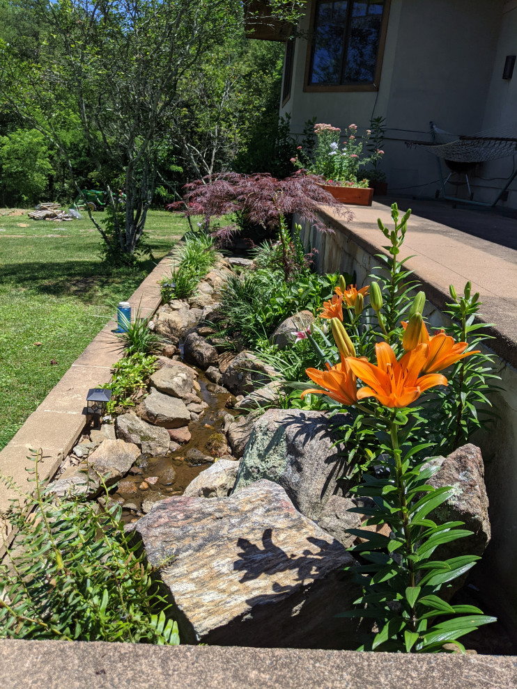 Photo of a medium sized world-inspired garden in Other with a waterfall.