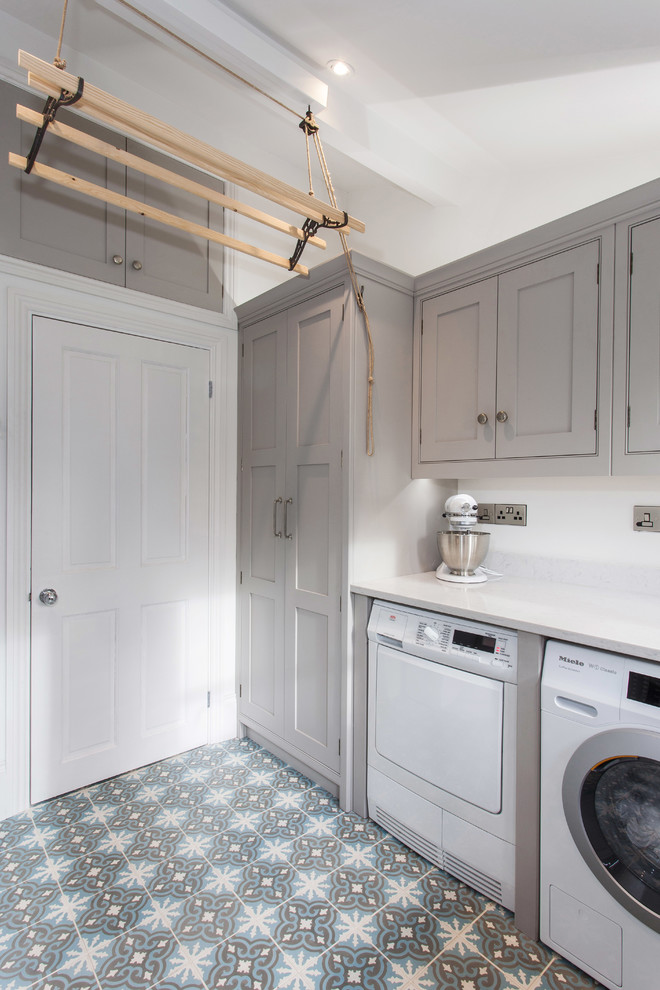 This is an example of a small traditional l-shaped dedicated laundry room in Kent with beaded inset cabinets, grey cabinets, quartzite benchtops, white walls, ceramic floors, a side-by-side washer and dryer and multi-coloured floor.
