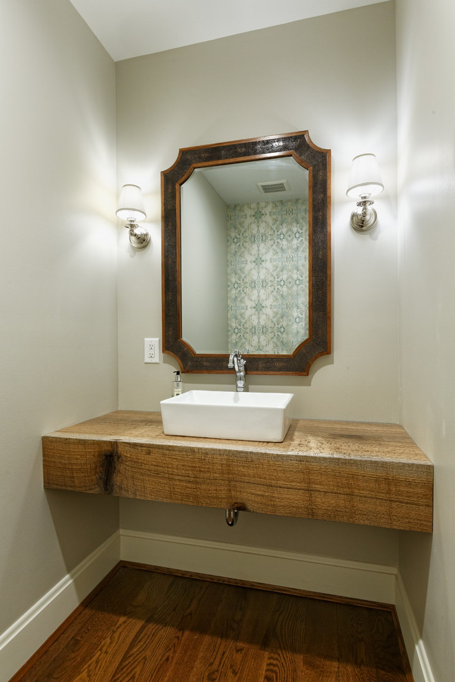 This is an example of a mid-sized country powder room in Cincinnati with grey walls, medium hardwood floors, a vessel sink and wood benchtops.