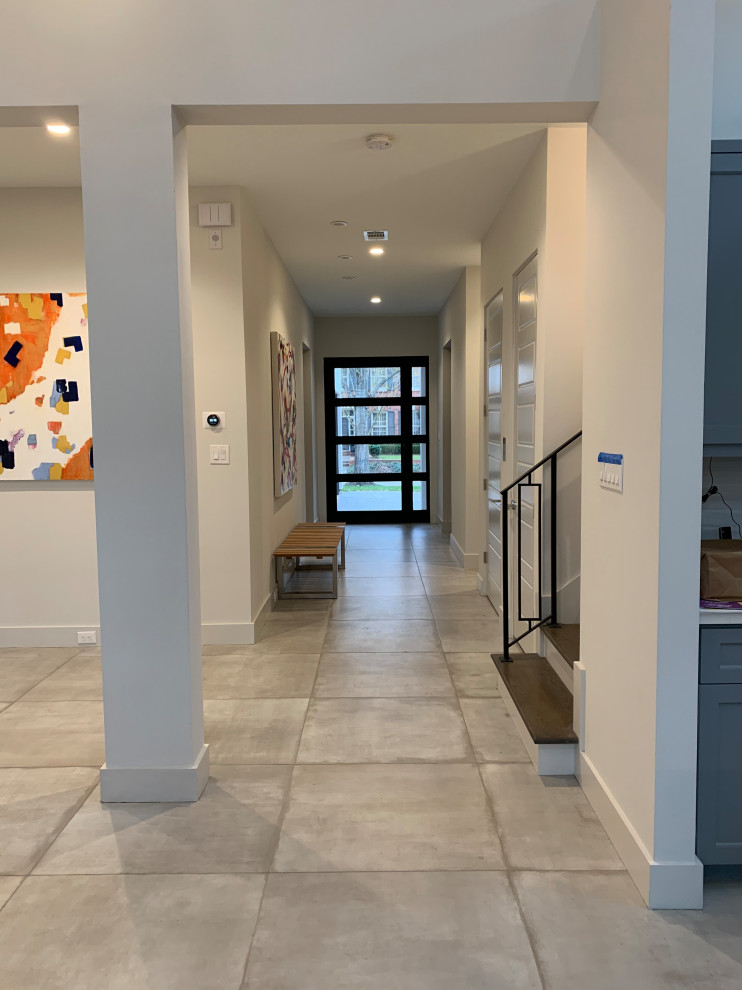 Cette image montre un hall d'entrée minimaliste avec un mur gris, un sol en carrelage de porcelaine, une porte simple, une porte en verre et un sol vert.
