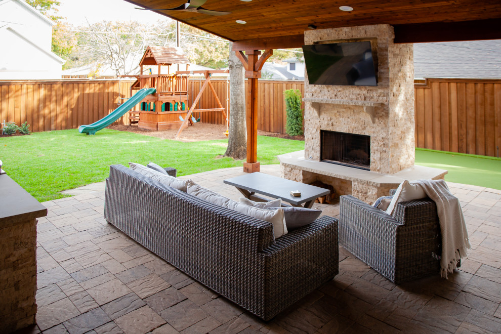 Inspiration for a transitional partial sun garden in Dallas with with fireplace, natural stone pavers and a wood fence.