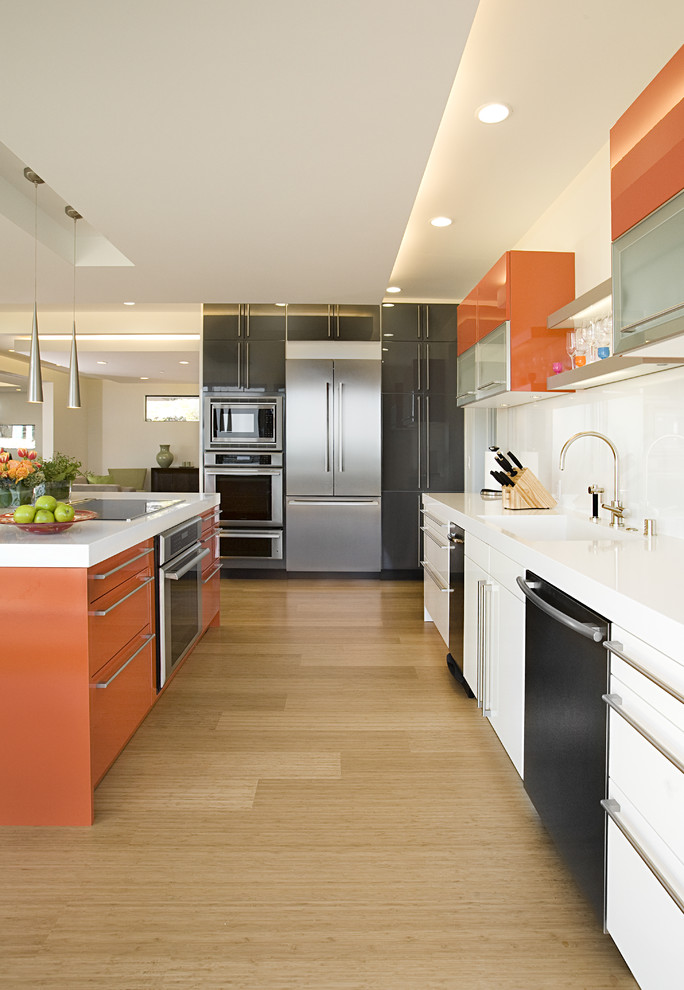 Mid-sized contemporary galley eat-in kitchen in San Francisco with stainless steel appliances, an integrated sink, flat-panel cabinets, orange cabinets, white splashback, bamboo floors and beige floor.