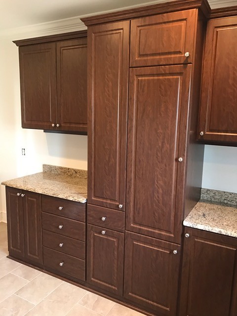 This is an example of a large traditional u-shaped utility room in Atlanta with raised-panel cabinets, dark wood cabinets, granite benchtops, beige walls, ceramic floors, a side-by-side washer and dryer, an undermount sink, beige floor and brown benchtop.