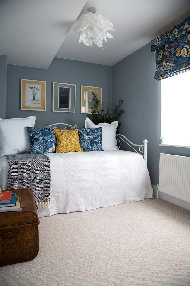 Mid-sized country bedroom in Kent with beige walls and carpet.