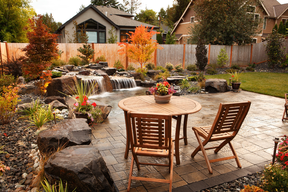 This is an example of a mid-sized contemporary backyard full sun garden for summer in Seattle with with pond and concrete pavers.
