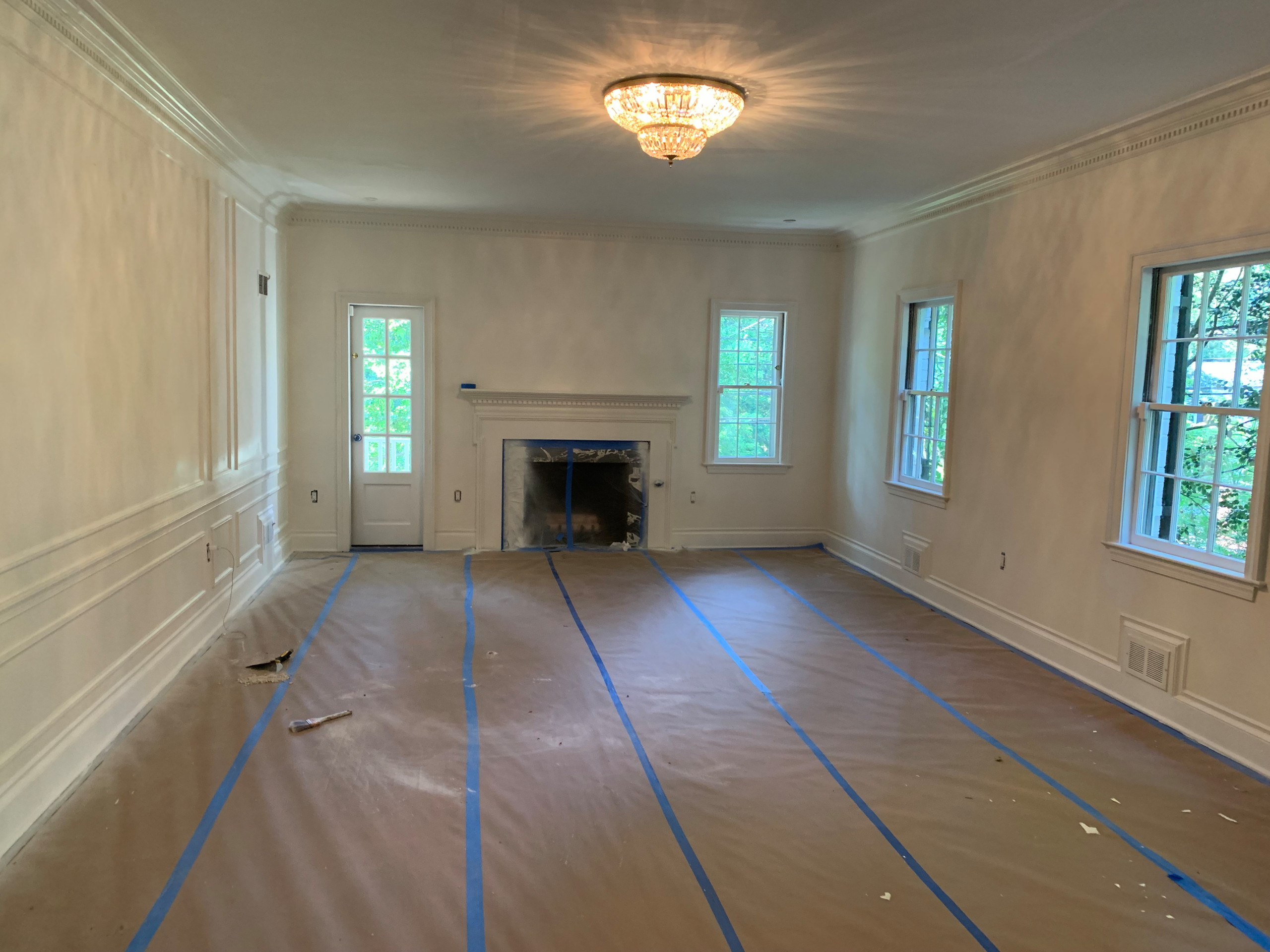 On the job photo: Finished spray painting all trim inside this living room. Floors are covered and walls and ceilings are primed and ready for paint.