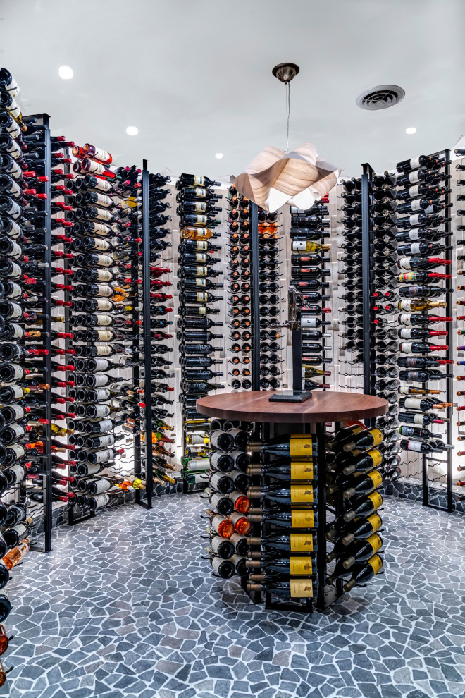 Example of a mid-sized mountain style concrete floor and gray floor wine cellar design in Columbus with storage racks