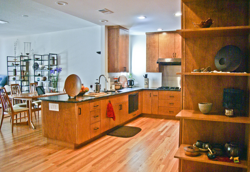 This is an example of a small contemporary u-shaped eat-in kitchen in Sacramento with a drop-in sink, flat-panel cabinets, medium wood cabinets, soapstone benchtops, black appliances, medium hardwood floors and a peninsula.