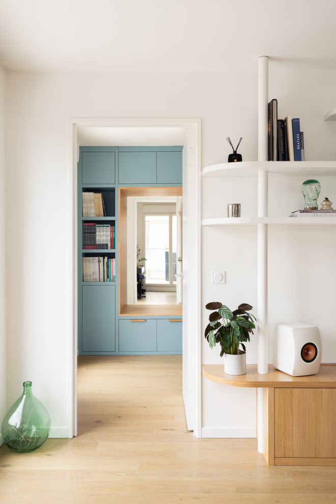 Mittelgroßes Nordisches Arbeitszimmer ohne Kamin mit Arbeitsplatz, blauer Wandfarbe, hellem Holzboden und Einbau-Schreibtisch in Paris
