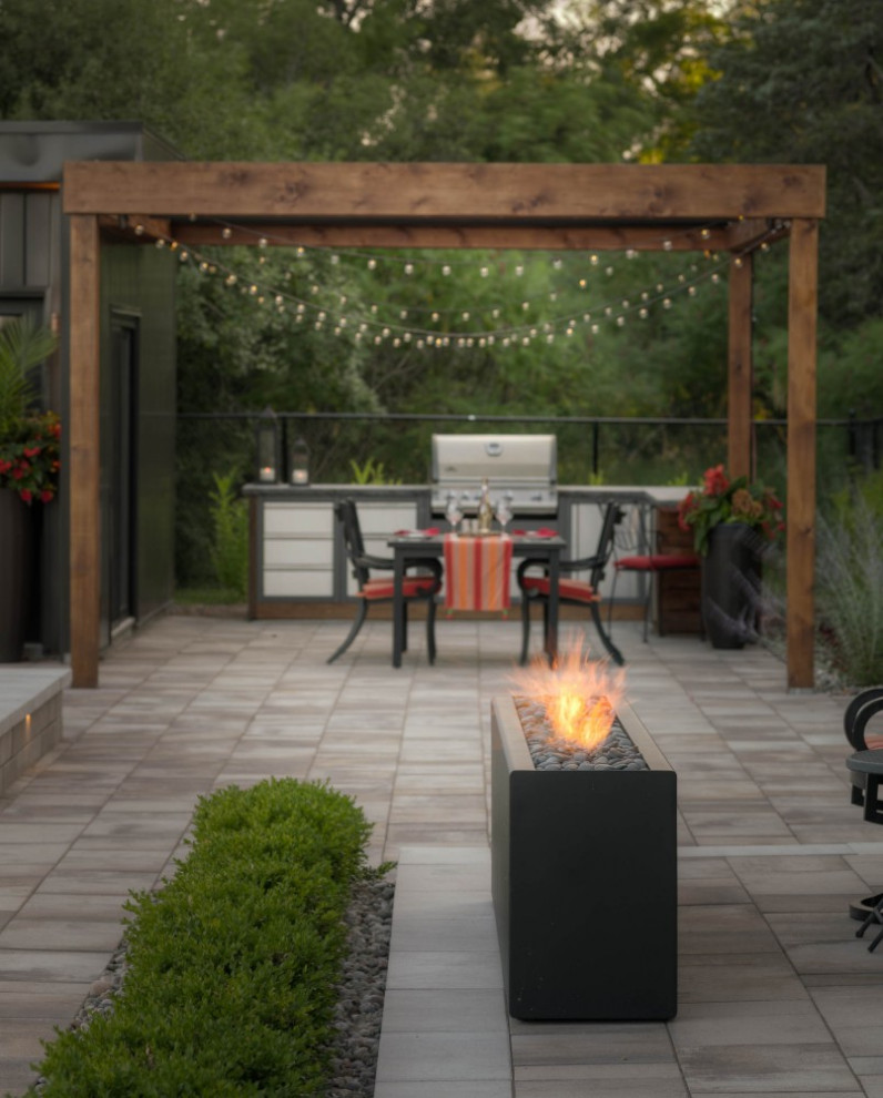 Design ideas for a large modern backyard patio in Toronto with with fireplace, natural stone pavers and a pergola.